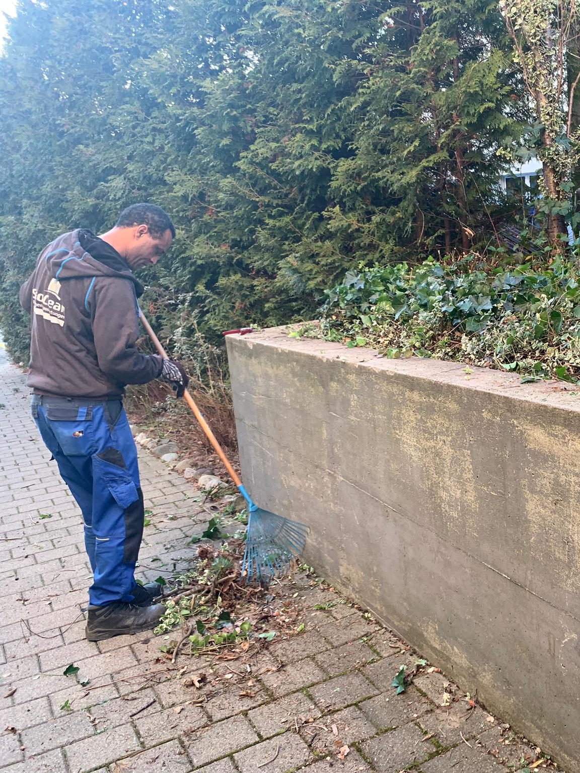 Mitarbeiter beim Zusammenwischen an einer Mauer